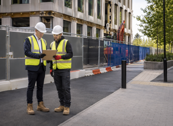 Client facilities manager and principal contractor reviewing plans beside a securely separated commercial refurbishment site